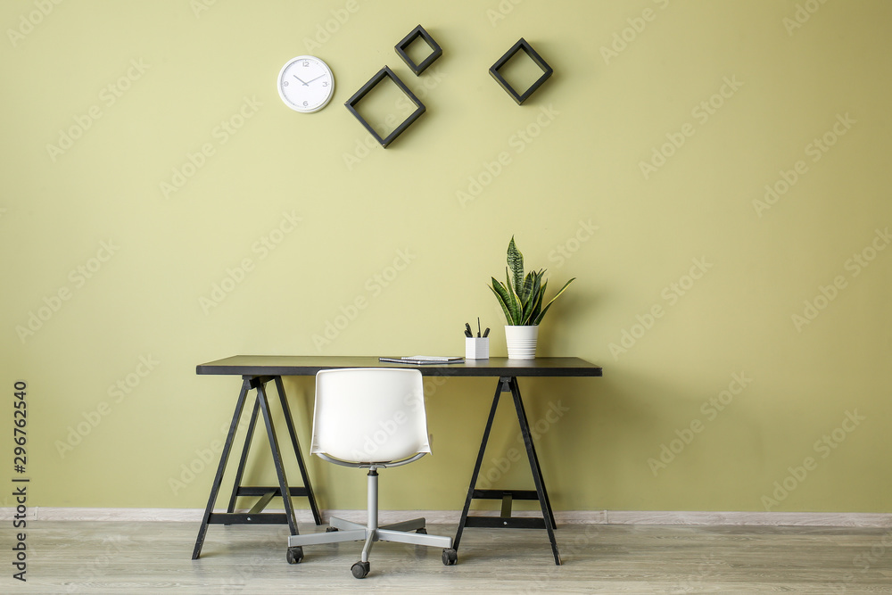 Table with chair and plant near color wall