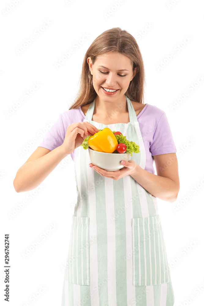 Beautiful young woman in apron and with vegetables on white background