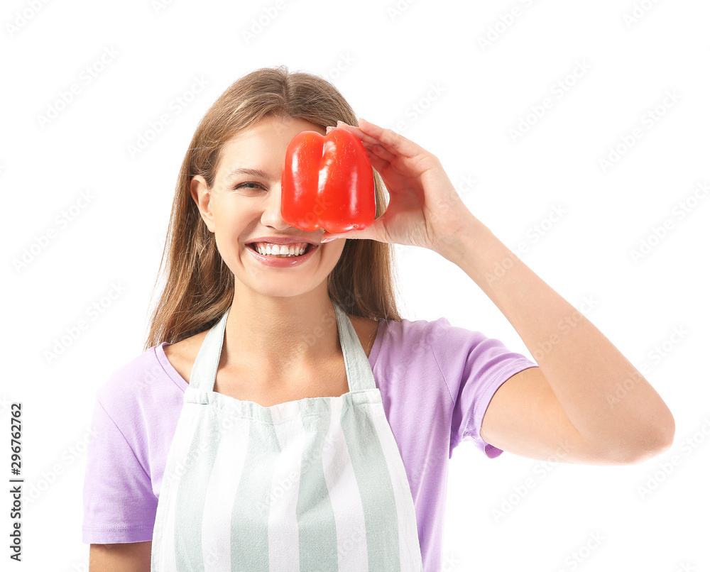 Beautiful young woman in apron and with pepper on white background