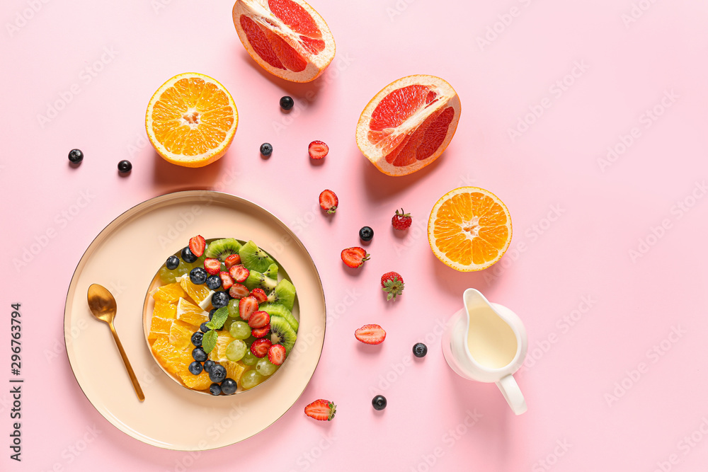 Plate with tasty fruit salad on color background