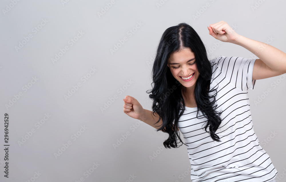 Young woman making a yay gesture on a gray background