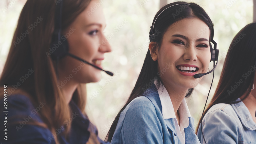 Customer support agent or call center with headset works on desktop computer while supporting the cu