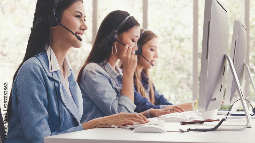 Customer support agent or call center with headset works on desktop computer while supporting the cu