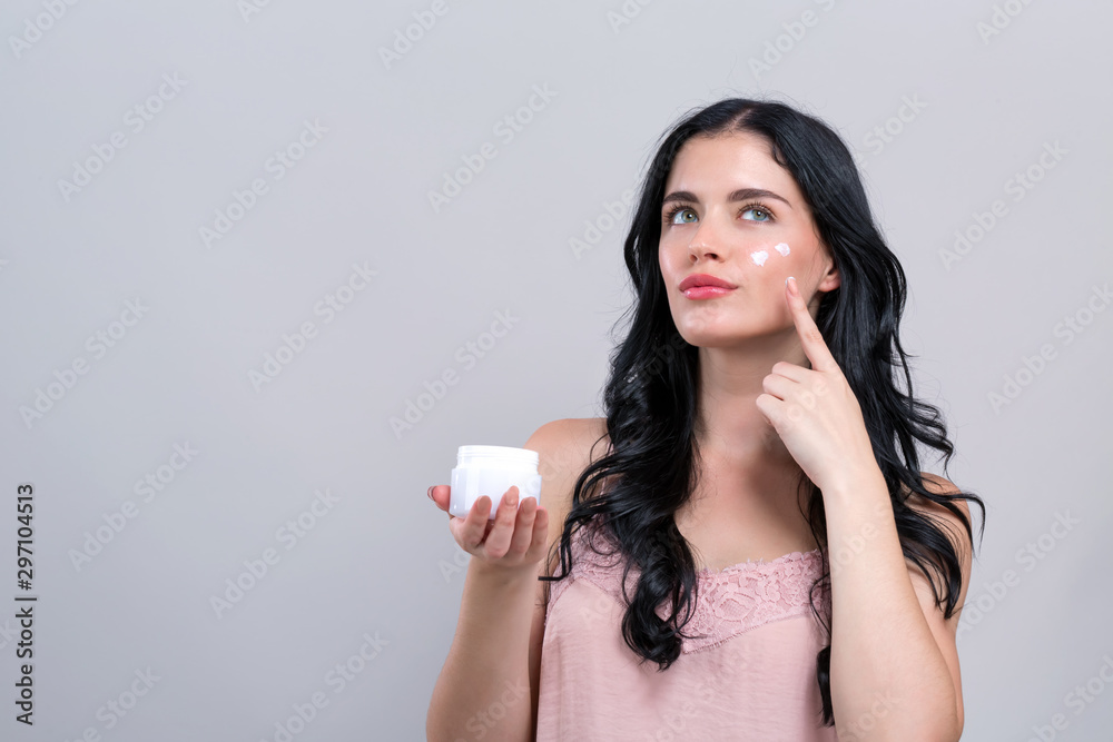 Beautiful young woman with skin care theme on a gray background