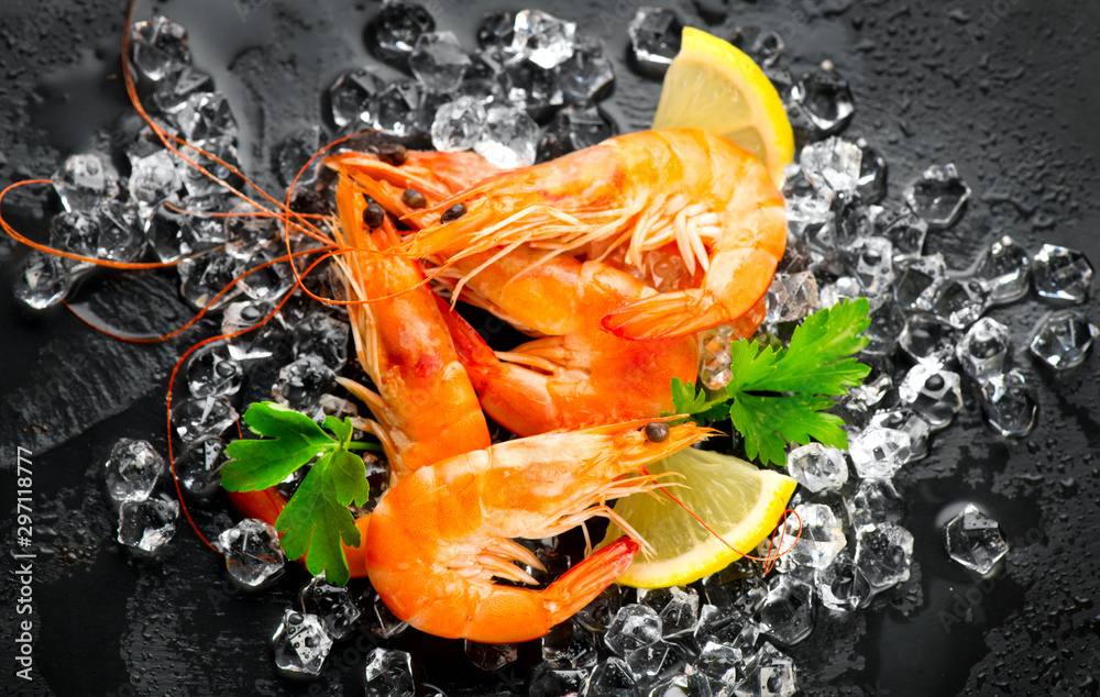 Shrimps. Fresh Prawns on a Black slate Background. Seafood on crashed ice served with herbs, dark ba