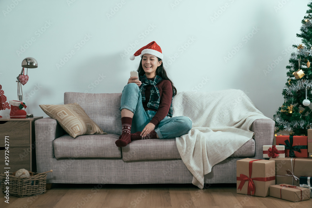 asian chinese woman in red sweater sitting on cozy couch using cellphone. girl on white background b