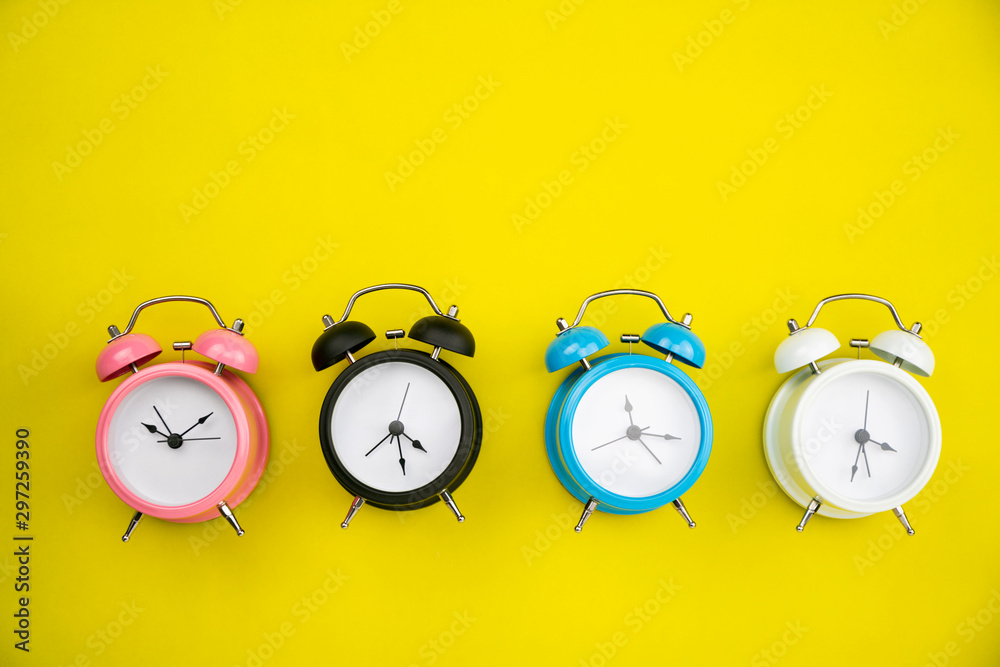 Flat lay of beautiful new alarm clock on yellow paper background