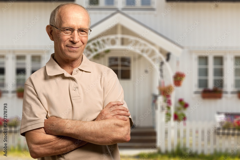 Handsome senior man standing on the house background