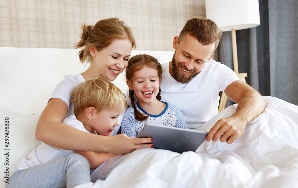 happy family laughing with tablet computer in bed at home. watching movies and   Internet