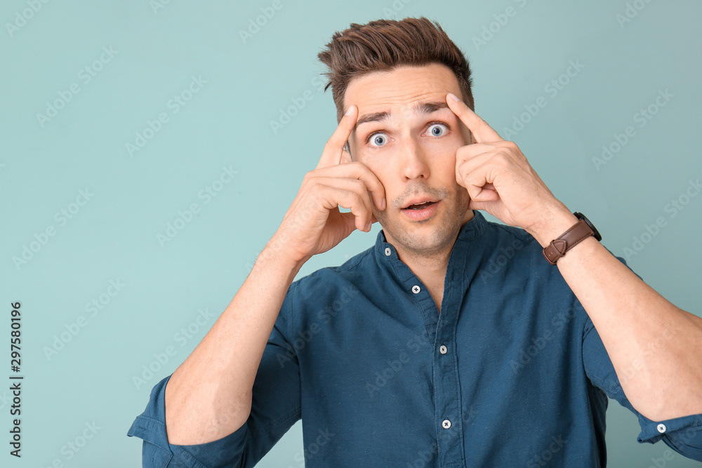 Surprised young man on color background