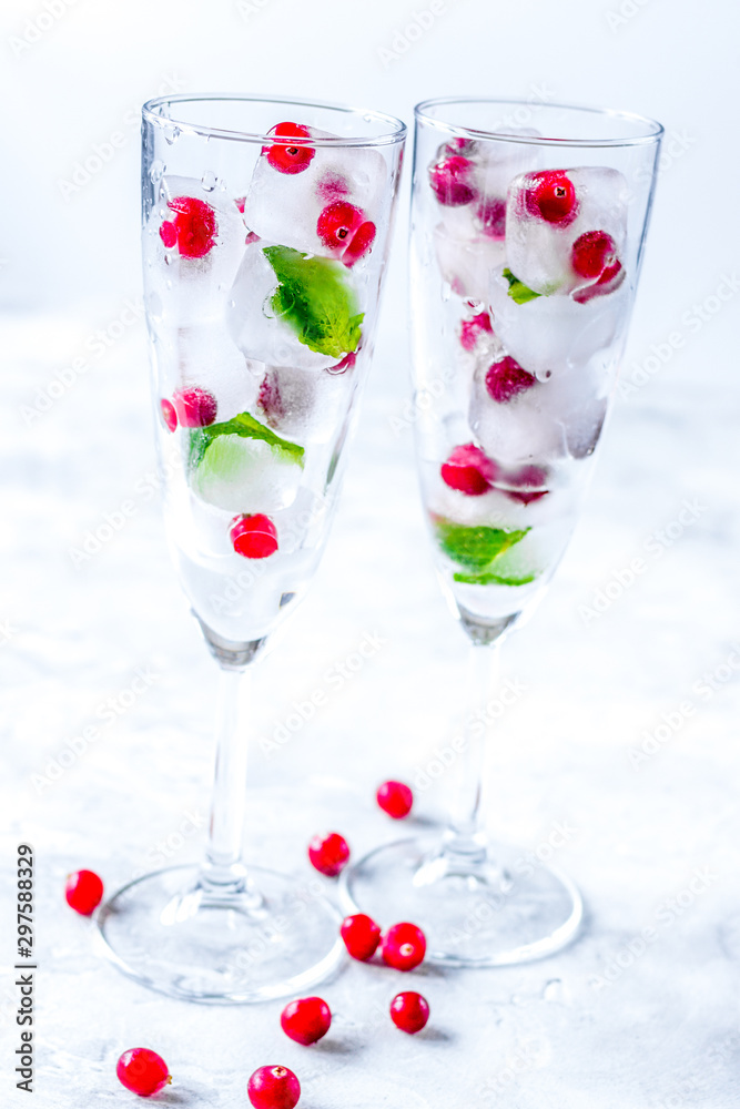 mint and red berries in ice cubes in glasses white background