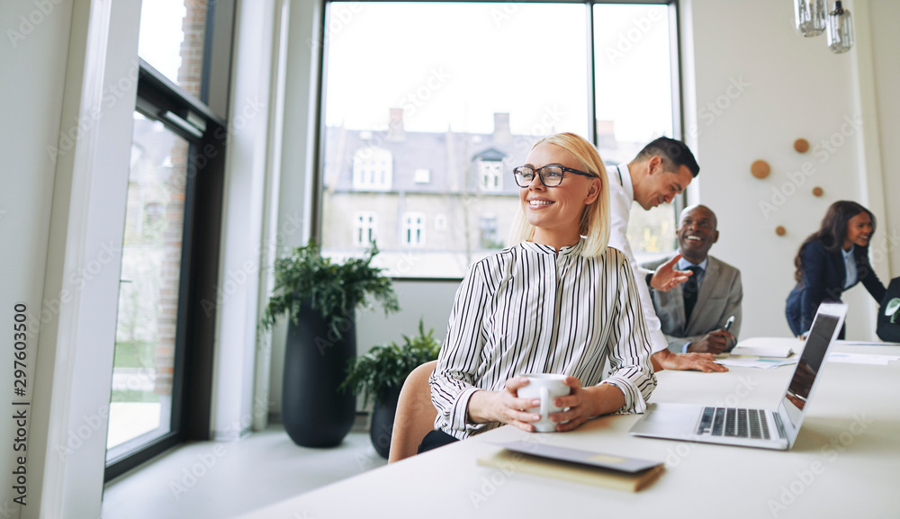 Smiling young businesswoman enjoying her coffee during an office