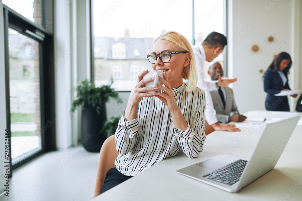 Smiling businesswoman drinking a coffee while working in an office