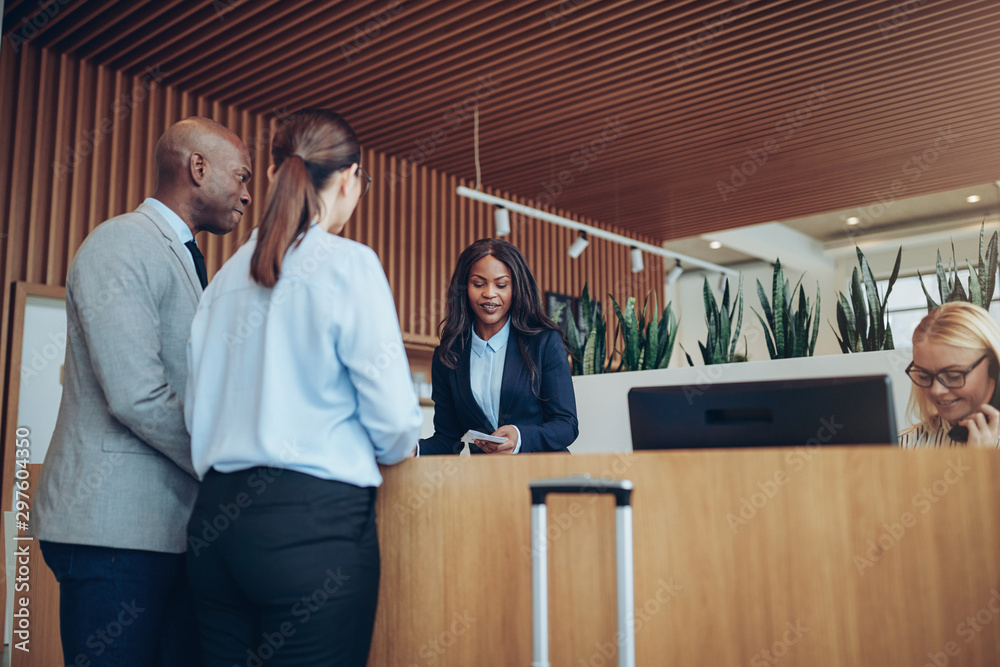 African American concierge checking in two smiling hotel guests