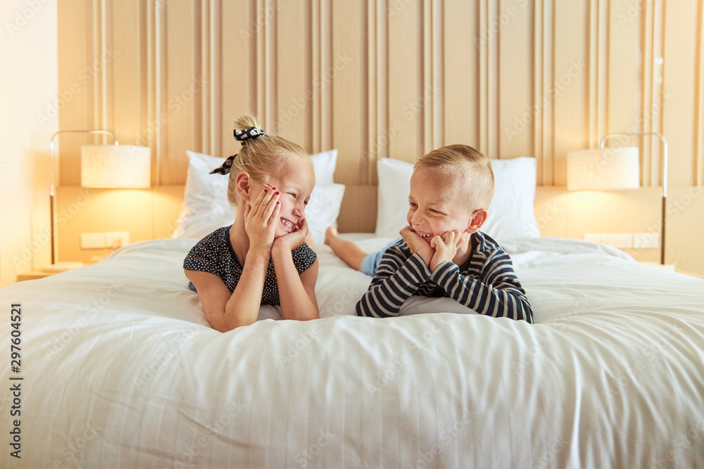 Smiling little brother and sister lying on their bed