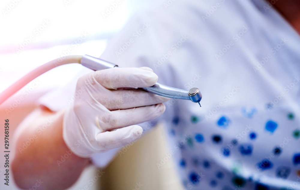 Mans hand in white gloves with special dental equipment ready to give professional treatment.