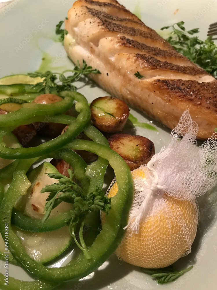 Grilled salmon with small unpeeled boiled potatoes with green pepper and lemon.