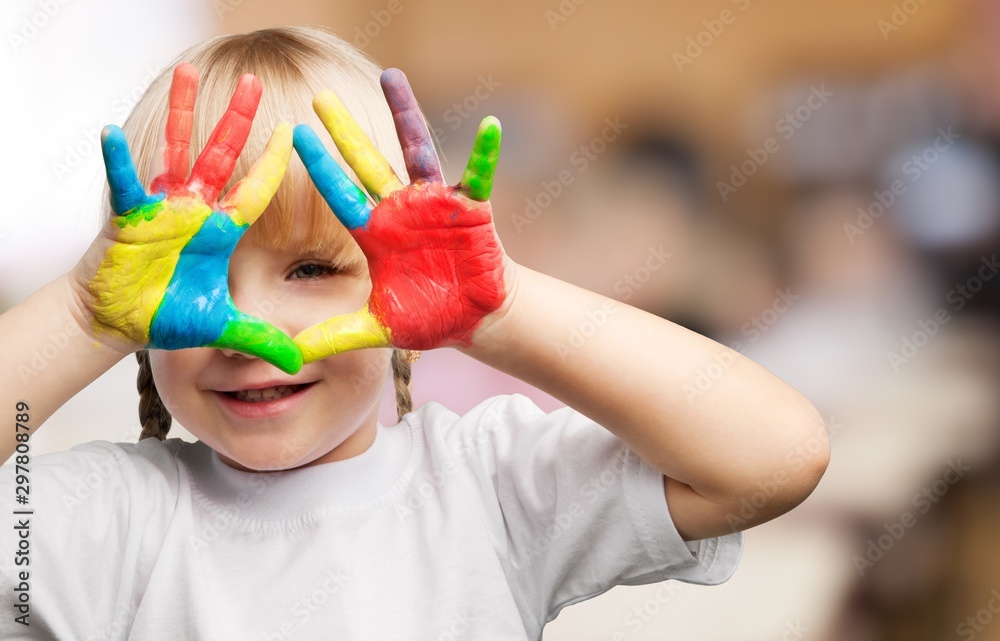 Cute little girl with colorful painted hands on class background