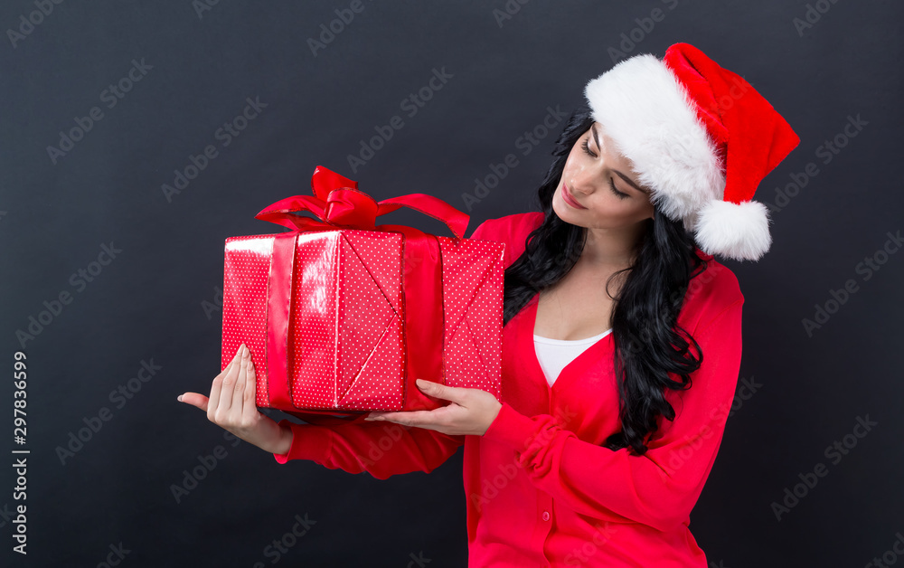 Young woman with santa hat holding a gift box on a black background