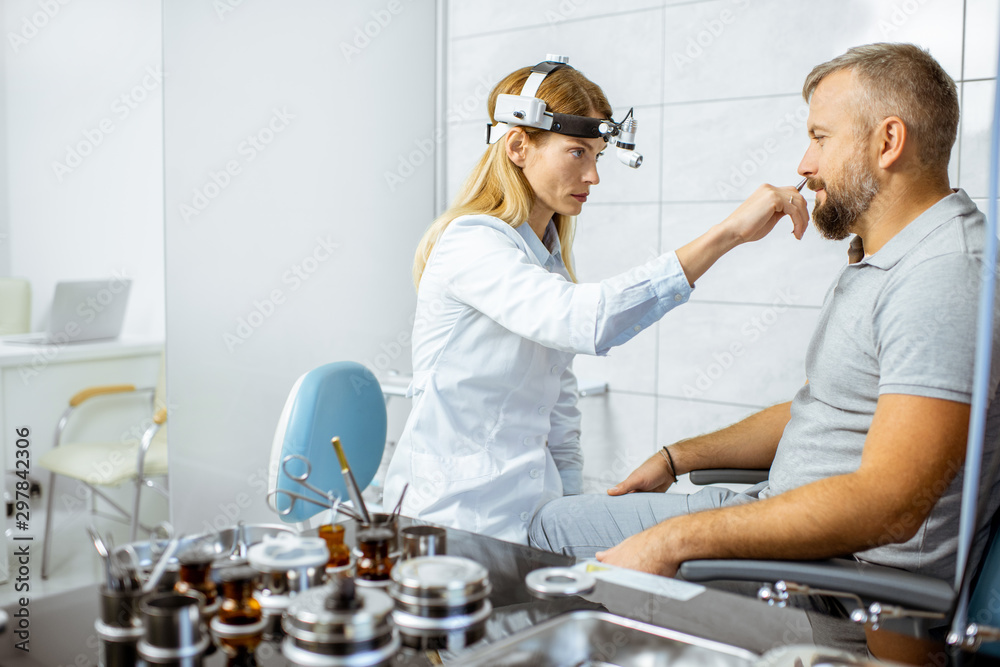 Female otolaryngologist with adult patient during a medical examination of a nose at the procedure r