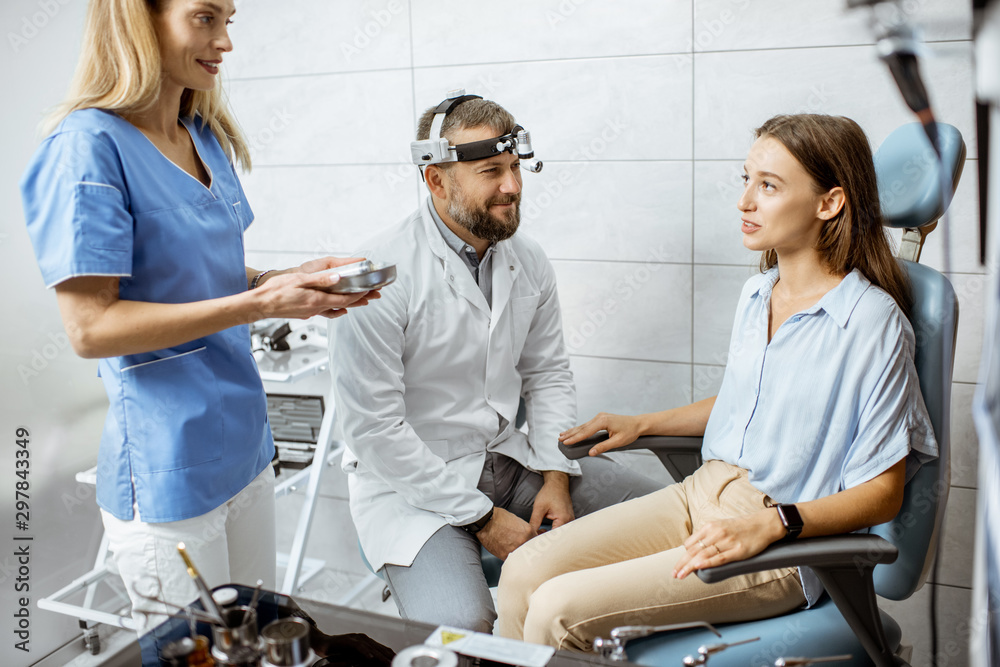 Patient with senior otolaryngologist and female assistant in ENT office during a medical examination