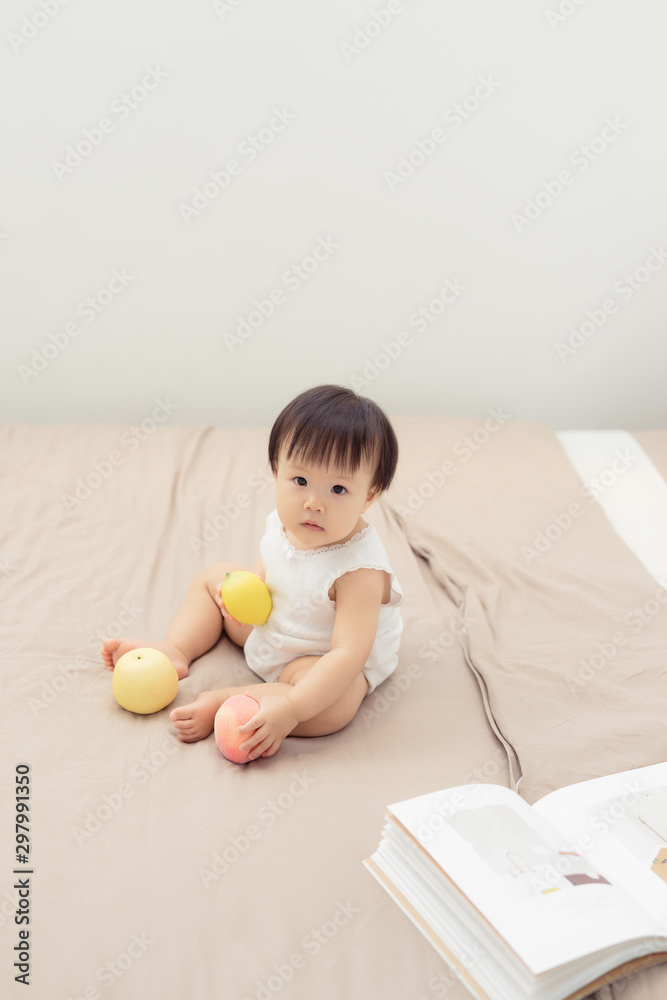 Portrait of baby girl playing with toy on bed at home