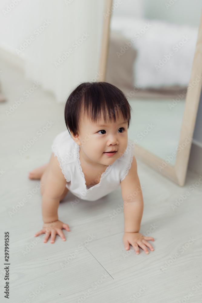 Adorable little baby girl crawling on floor in room