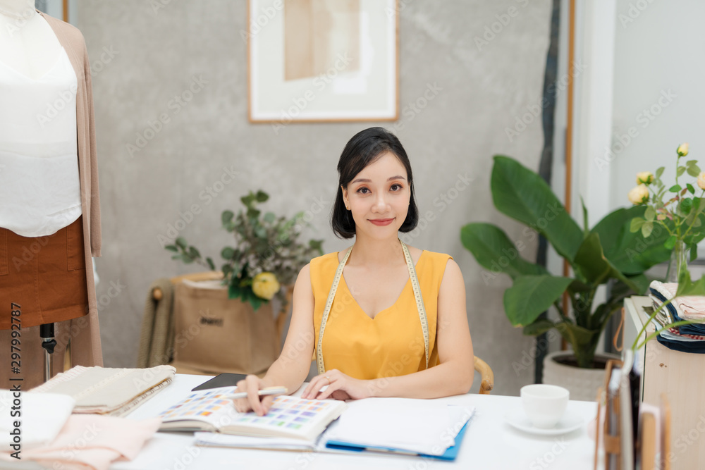 Portrait of a young fashion designer working on her atelier