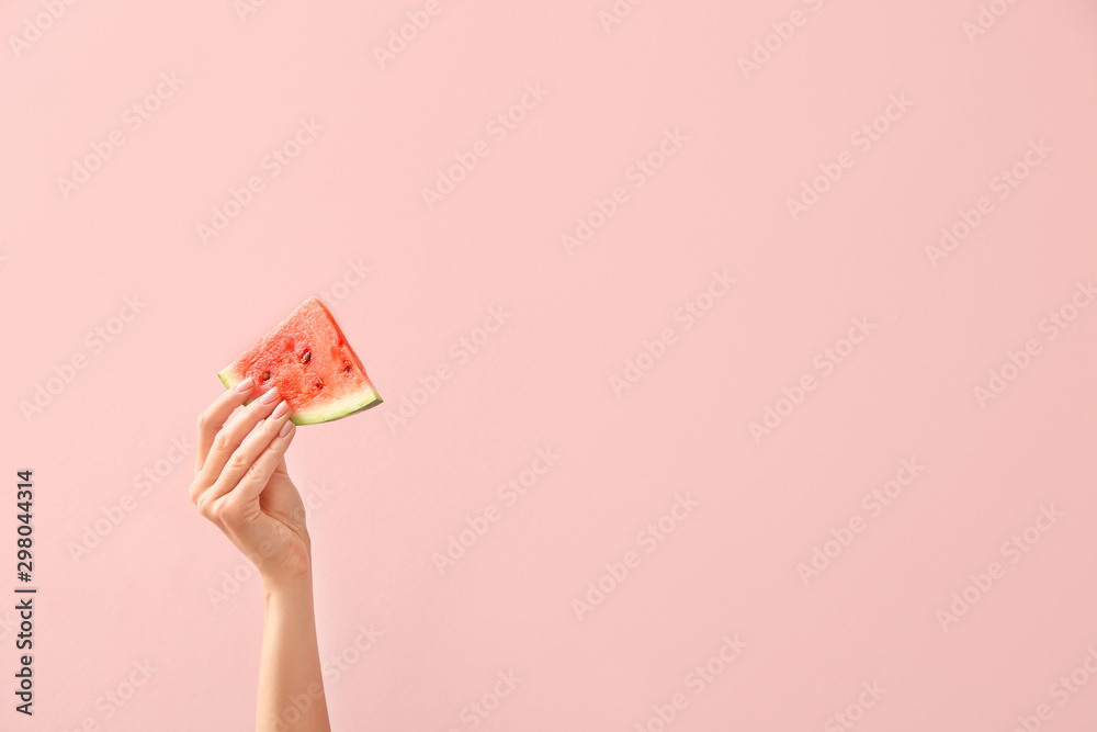 Female hand with piece of juicy watermelon on color background