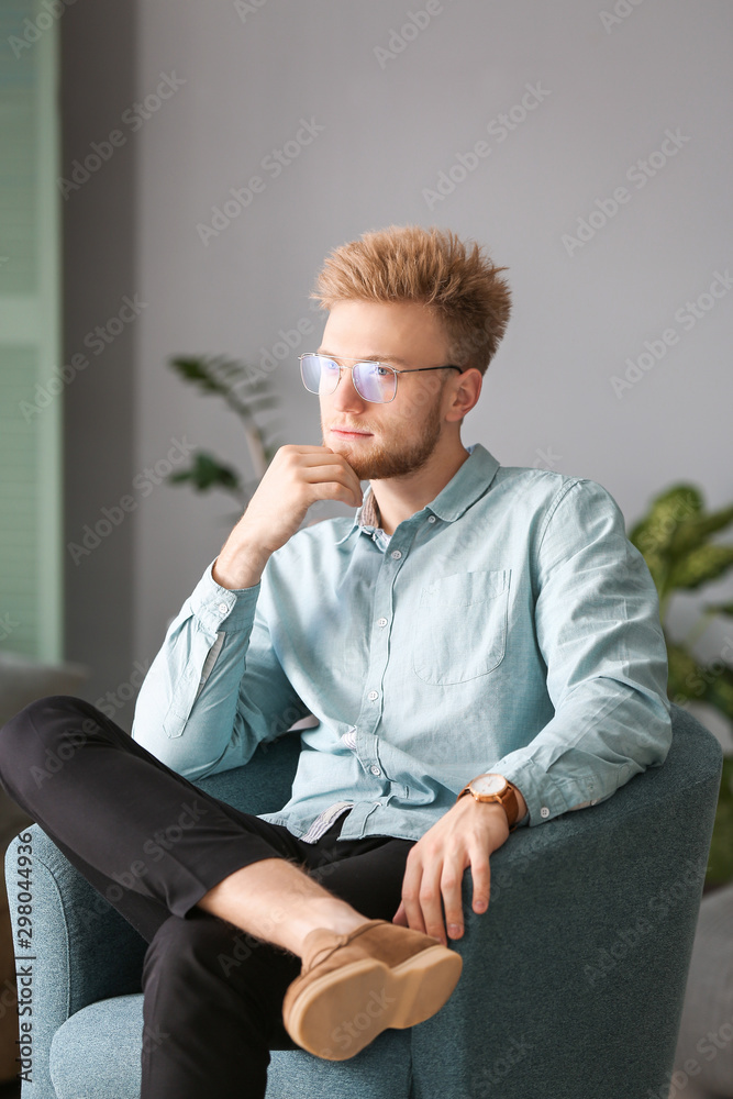 Portrait of stylish young man sitting in armchair at home