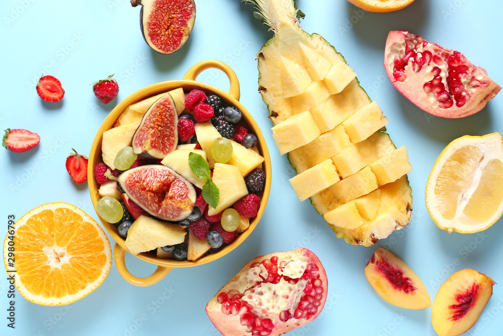 Pot with tasty fruit salad on color background