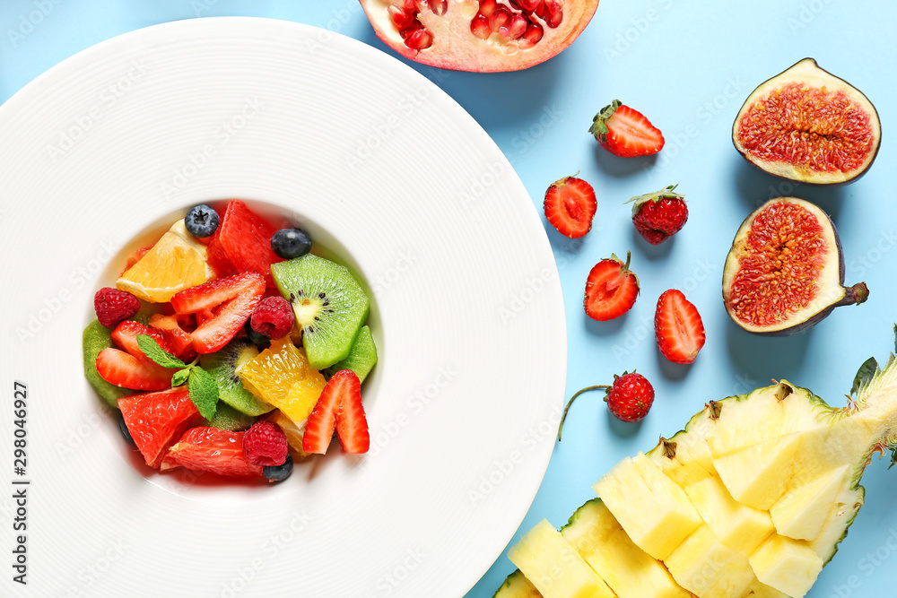 Plate with tasty fruit salad on color background