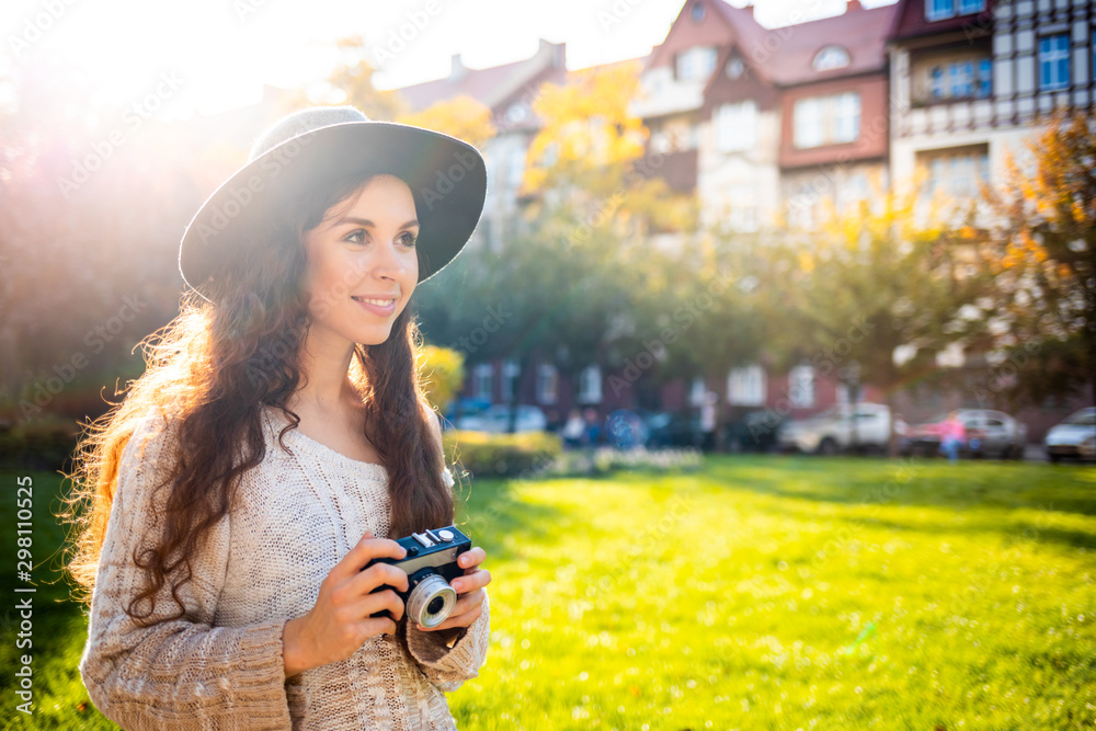 Lifestyle portrait of stylish girl with retro camera during walk in city street