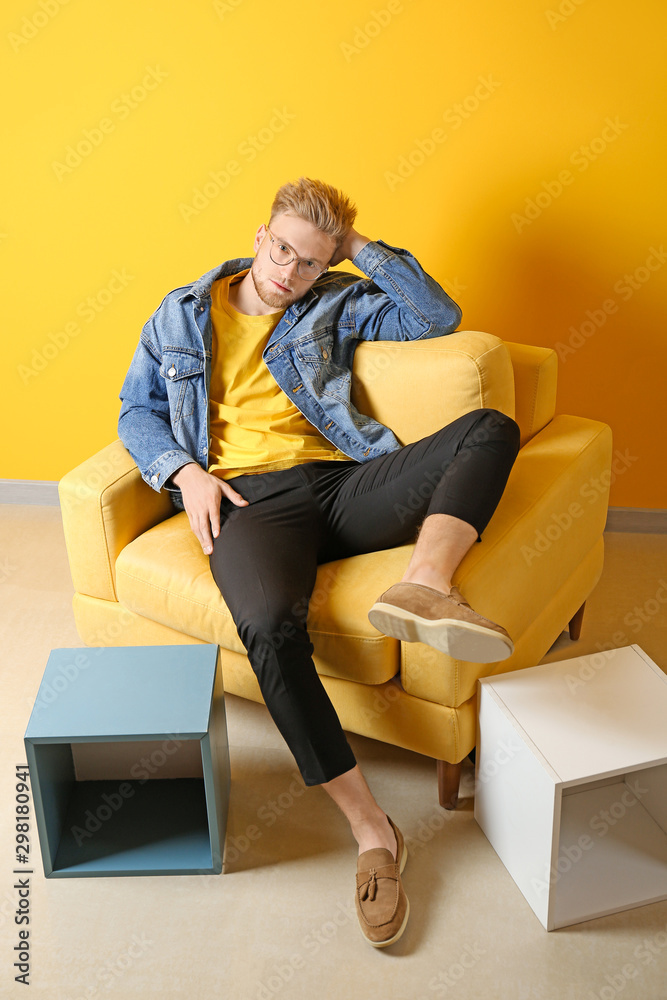 Portrait of stylish young man sitting in armchair indoors