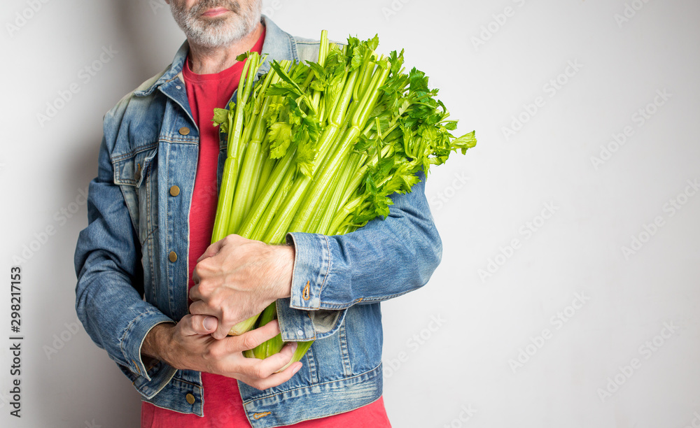 男子手持新鲜芹菜，白底隔离，休闲风格，健康生活方式，健康