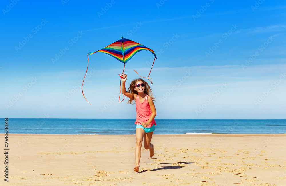 Happy little girls run with cute kite on the sand