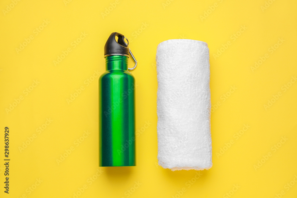 Sports water bottle and towel on color background