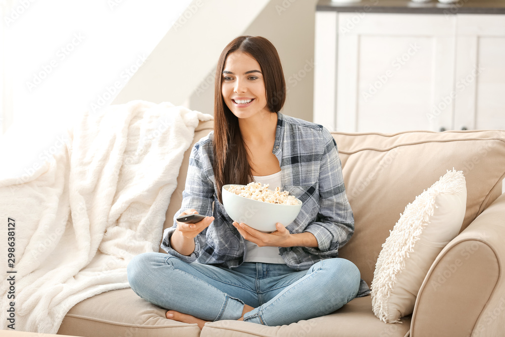 Young woman with popcorn watching movie at home