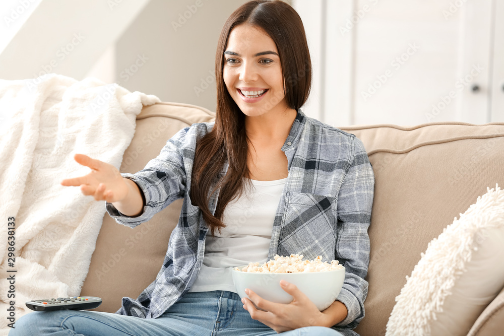 Young woman with popcorn watching movie at home