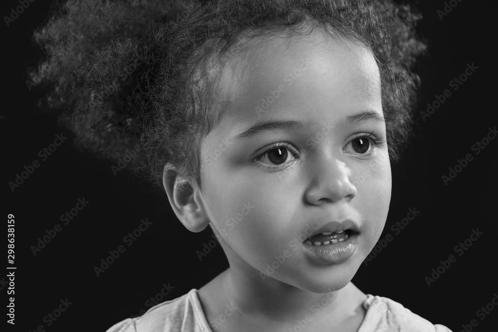 Black and white portrait of little African-American girl on dark background