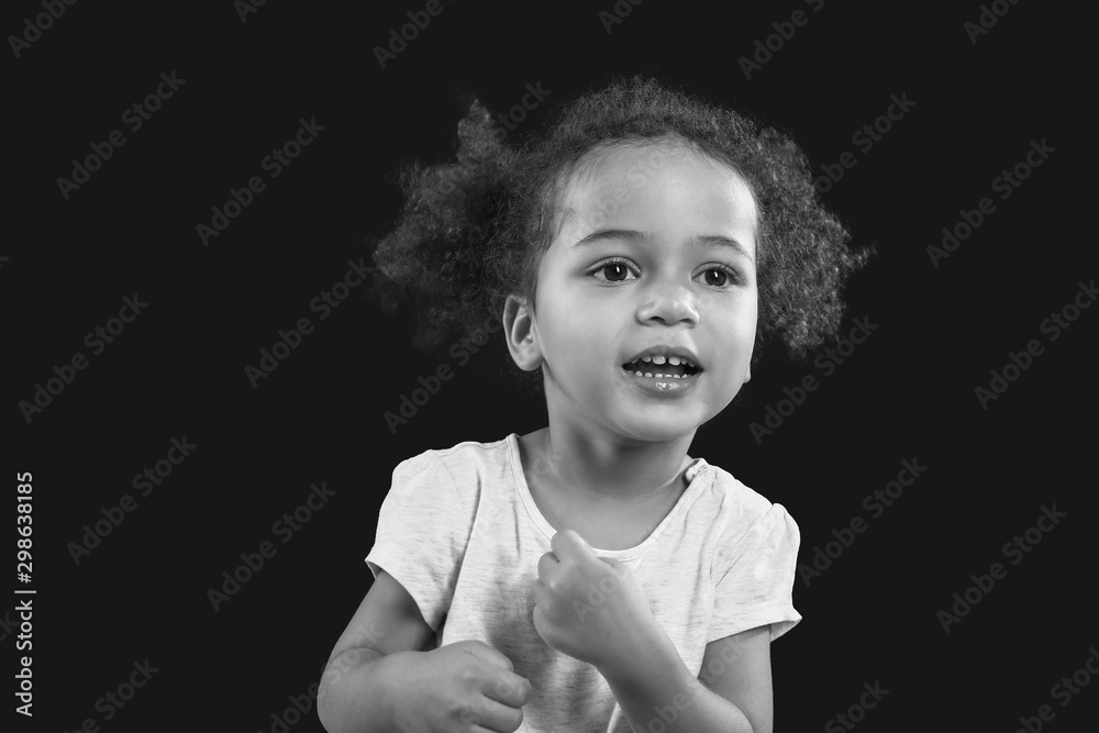 Black and white portrait of little African-American girl on dark background