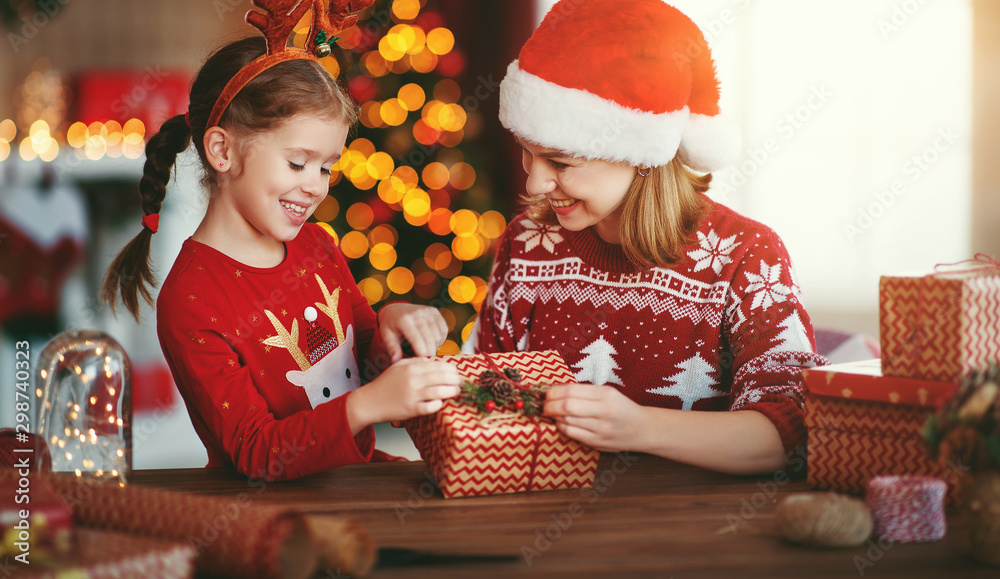 happy family mother and child pack Christmas gifts at home near Christmas tree.