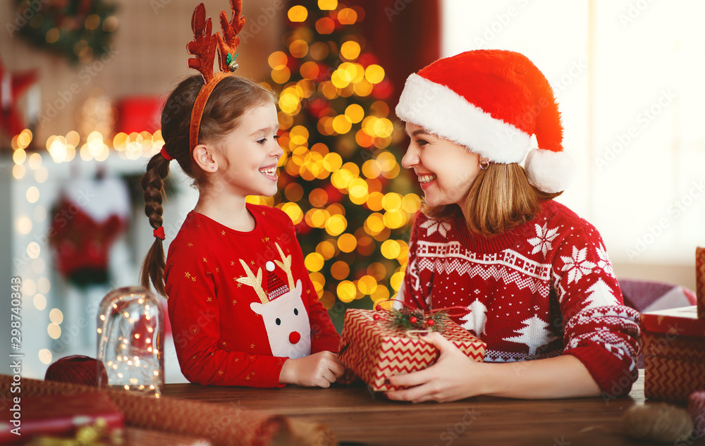 happy family mother and child pack Christmas gifts at home near Christmas tree.