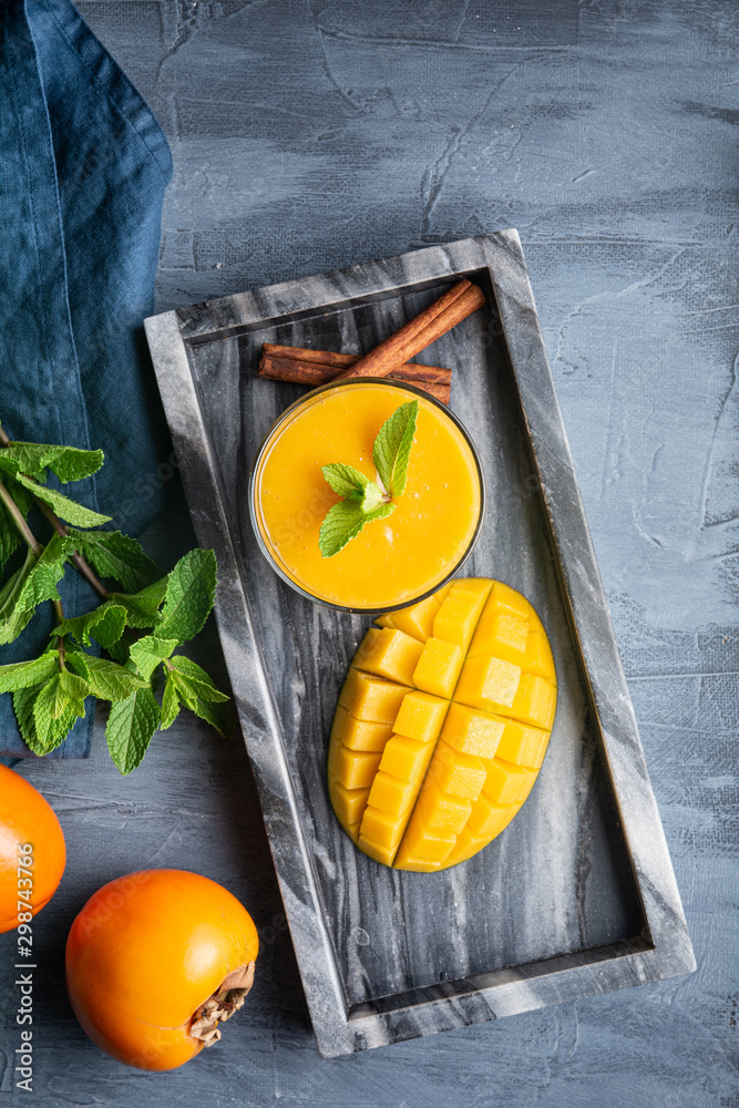 Spicy mango and persimmon smoothie with ginger and cinnamon in a glass jar for immunity and digestio