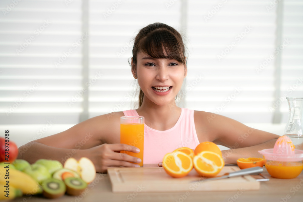 Asian girl make an orange juice by hand at home after finished exercise