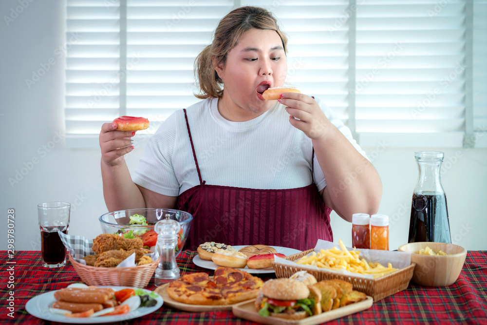 亚洲胖女孩饿了，吃了桌上的垃圾食品