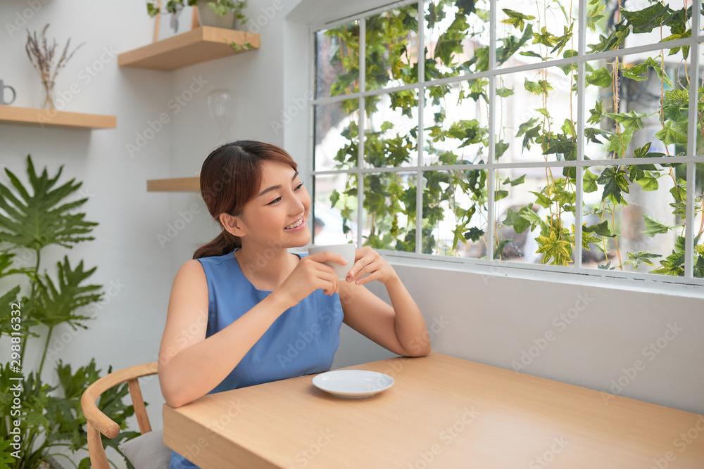 Beautiful Asian woman drinking coffee behind the green window