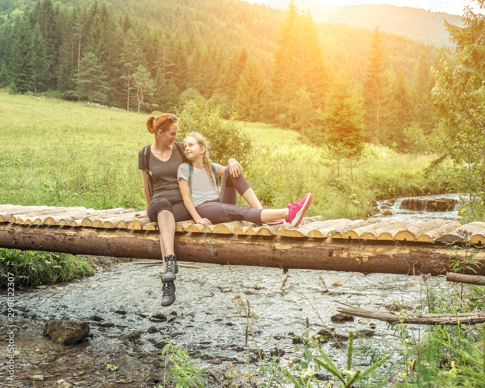 Mother and Douther Hikers with backpacks sitting and relaxing on