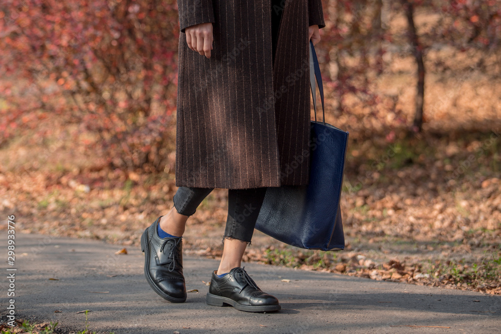 Closeup legs fashionable woman wear black  shoes and brown coat. Stylish fall  outfit