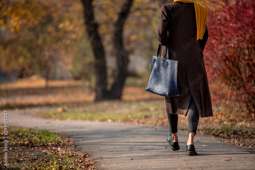  Fashionable autumn woman in trendy fall outfit walking in autumn park